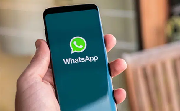 hand holding a mobile phone with whats app on the screen